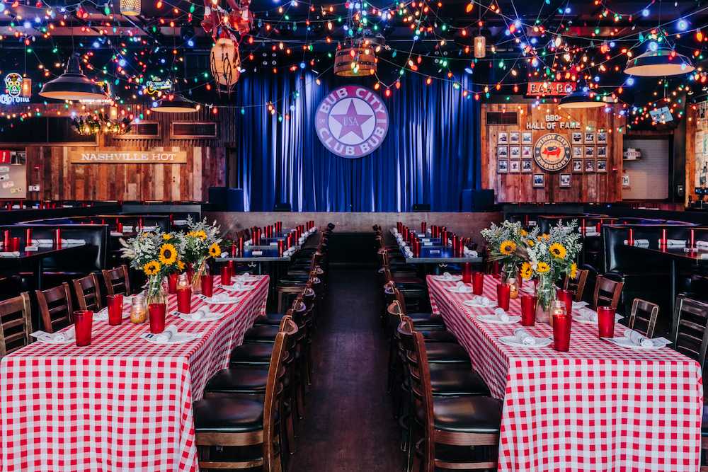in a large room there are many tables with checkered table cloths nd set with red cups and plates
